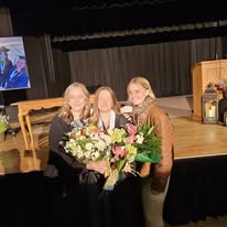 Three women with flowers at a gathering