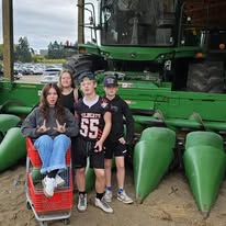 Family members standing beside farm equipment